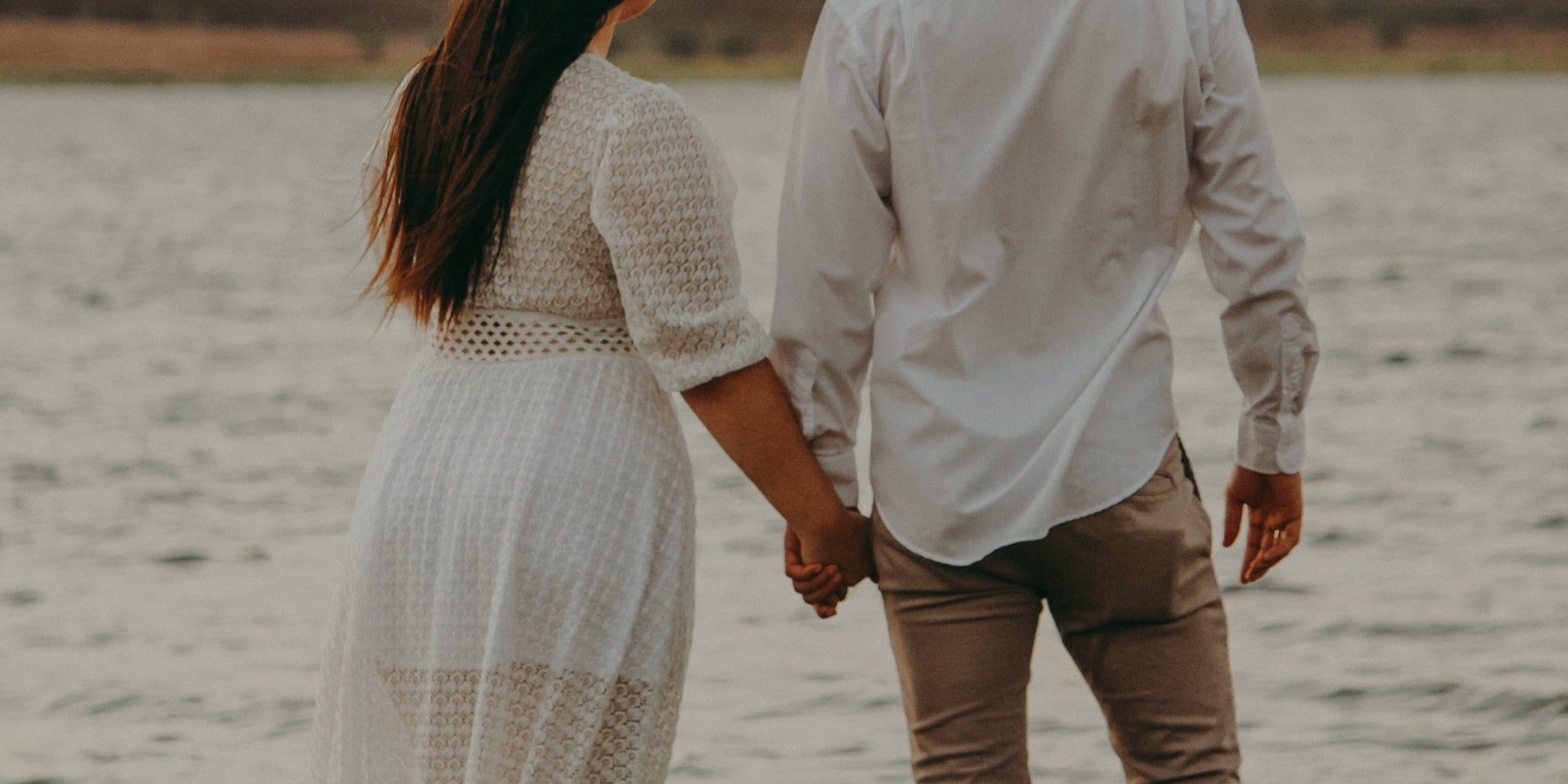 photo of a couple holding hands by the water