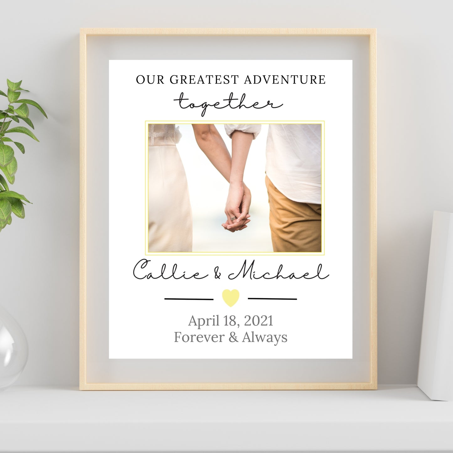 Framed print with a couple holding hands, personalized text, and a plant on the side.