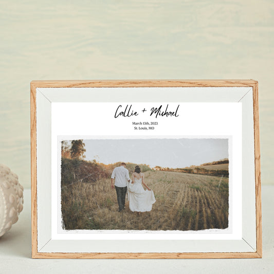 A framed photo of a couple standing in a field, with a customizable text label that includes names and a date.