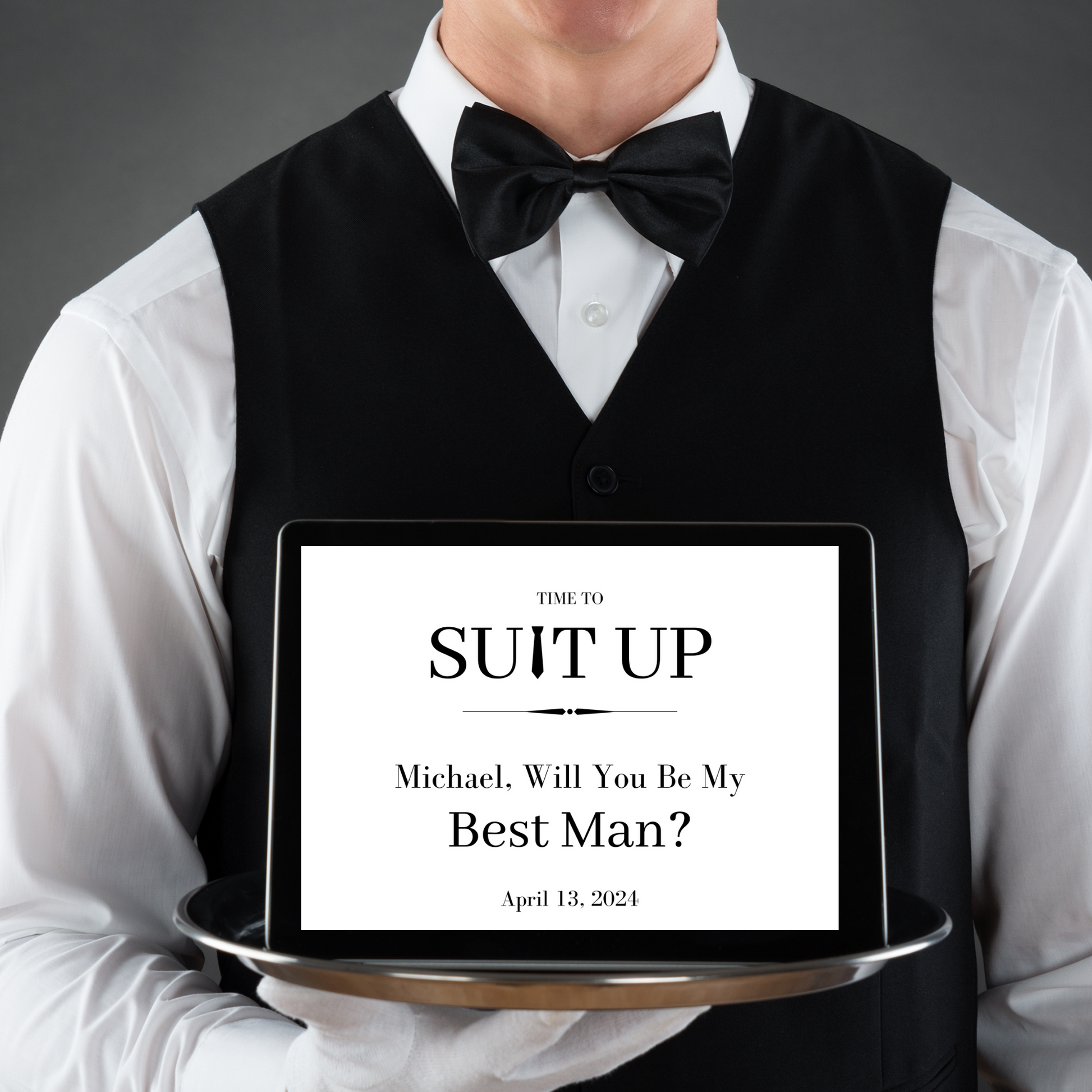 Man in formal attire holding a tray with a Best Man proposal message.